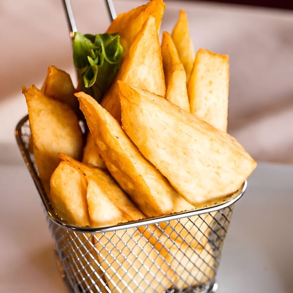 Golden brown, thick-cut Drelyse African Restaurant fries in a metal basket with a lettuce garnish.